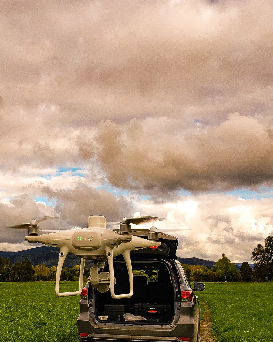 Dron de fotogrametría listo para volar sobre el maletero de una camioneta, bajo un cielo cubierto.