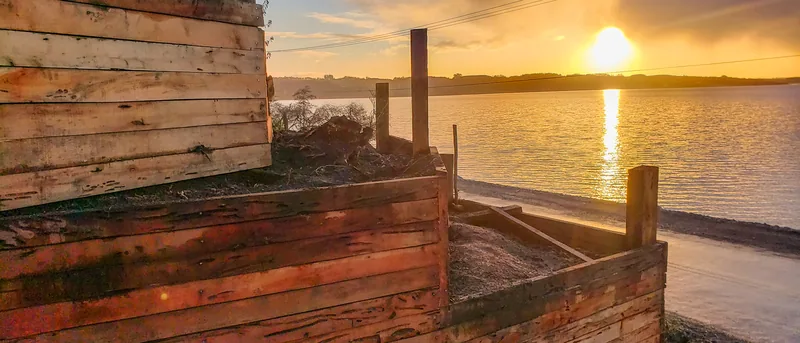 Muro de madera en curva frente al lago, al atardecer.
