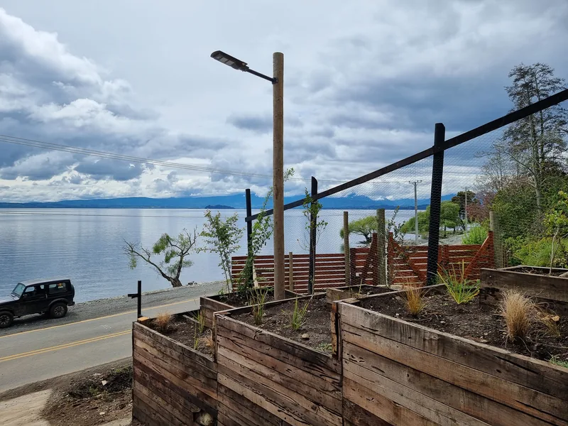 Muro de madera y sendero de gravilla con el lago detrás.