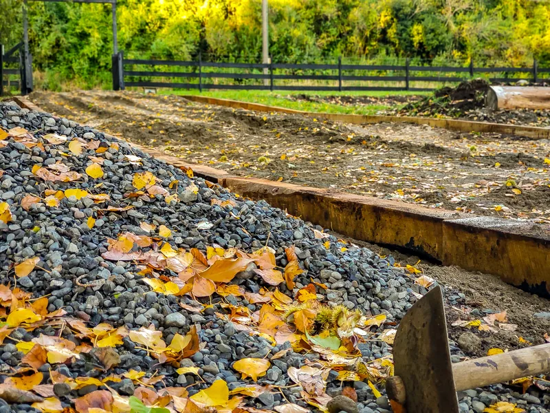 Borde de madera y gravilla cubiertos de hojas amarillas de otoño.